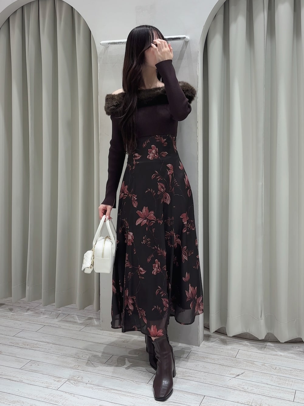 ブラウン系のワンピース、ホワイト系のハンドバッグ、ブラウン系のブーツを着用したレディースの冬コーディネートの3枚目の写真