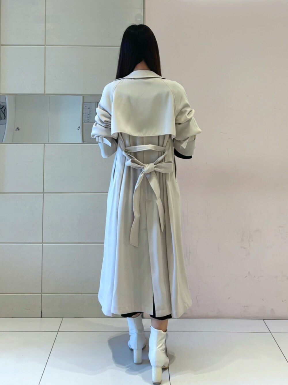 ホワイト系のブーツ、ブラック系のワンピース、ホワイト系のトレンチコートを着用したレディースの冬コーディネートの6枚目の写真