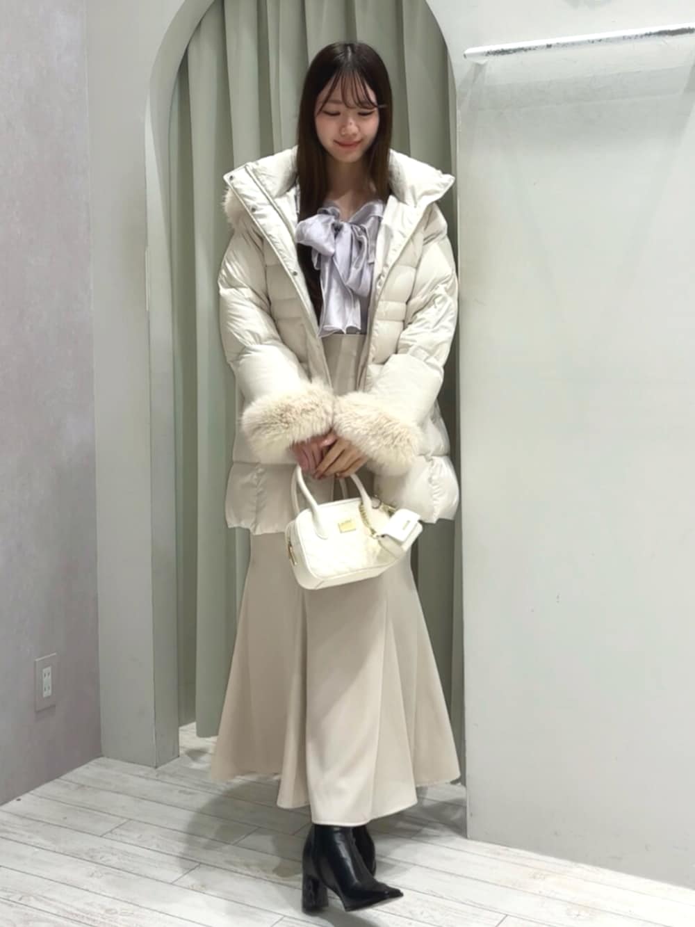 ホワイト系のハンドバッグ、ブラック系のブーツ、ホワイト系のダウンジャケット/コートを着用したレディースの秋コーディネートの7枚目の写真