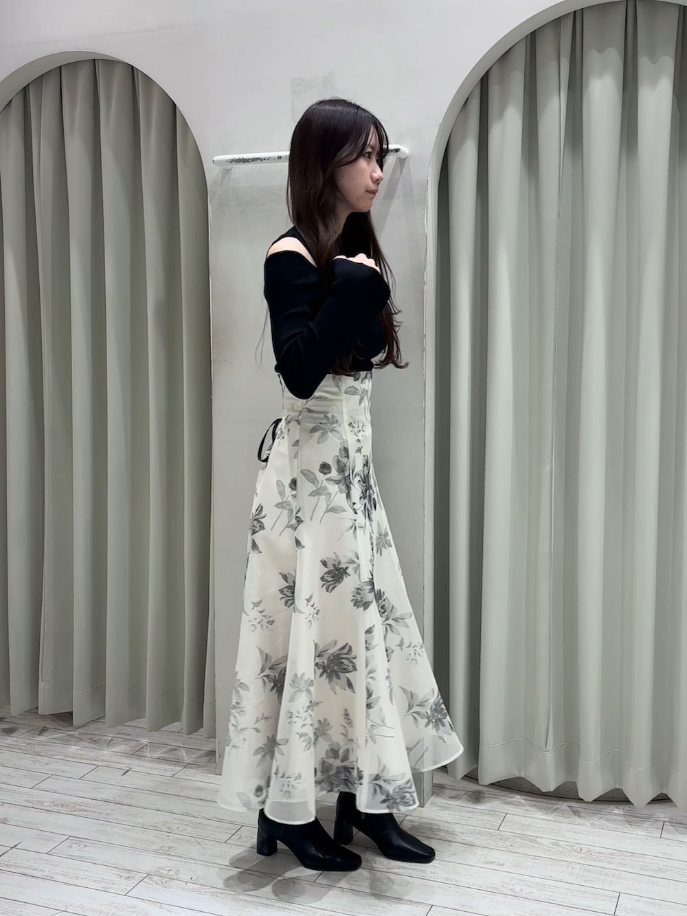 ブラック系のニット/セーター、ホワイト系のスカート、ブラック系のブーツを着用したレディースの春コーディネートの7枚目の写真