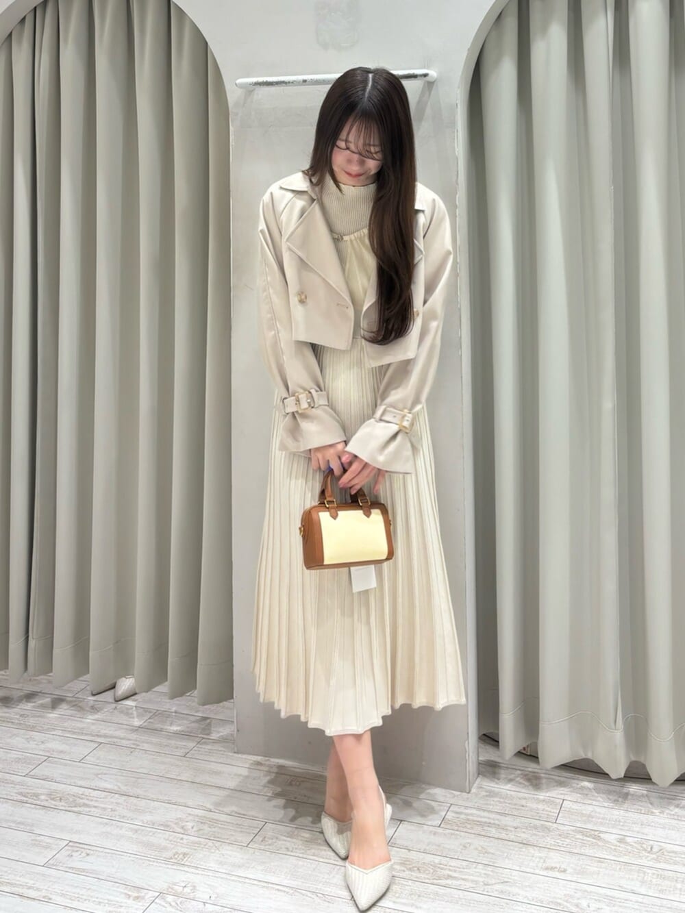 ブラウン系のハンドバッグ、ホワイト系のパンプス、ベージュ系のトレンチコートを着用したレディースの春コーディネートの2枚目の写真