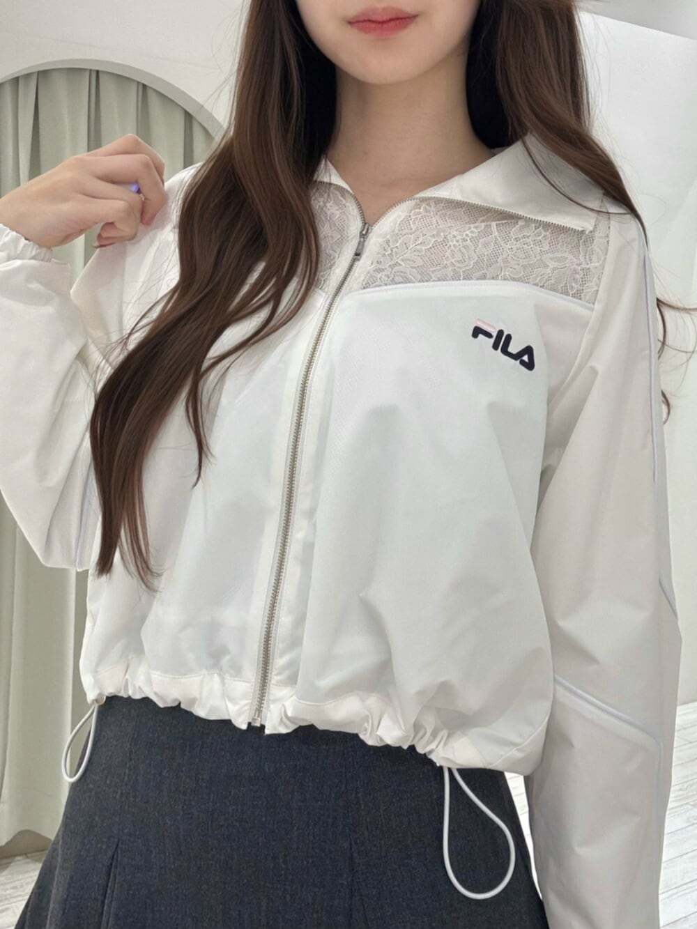 ブラック系のブーツ、ホワイト系のナイロンジャケット、グレー系のスカートを着用したレディースの冬コーディネートの6枚目の写真