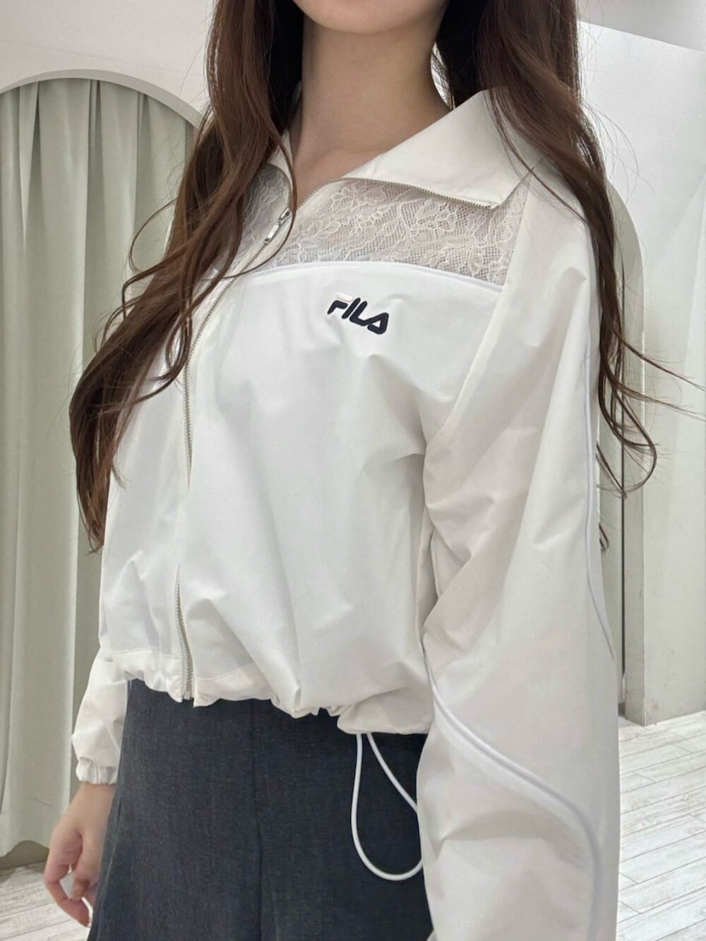 ブラック系のブーツ、ホワイト系のナイロンジャケット、グレー系のスカートを着用したレディースの冬コーディネートの7枚目の写真