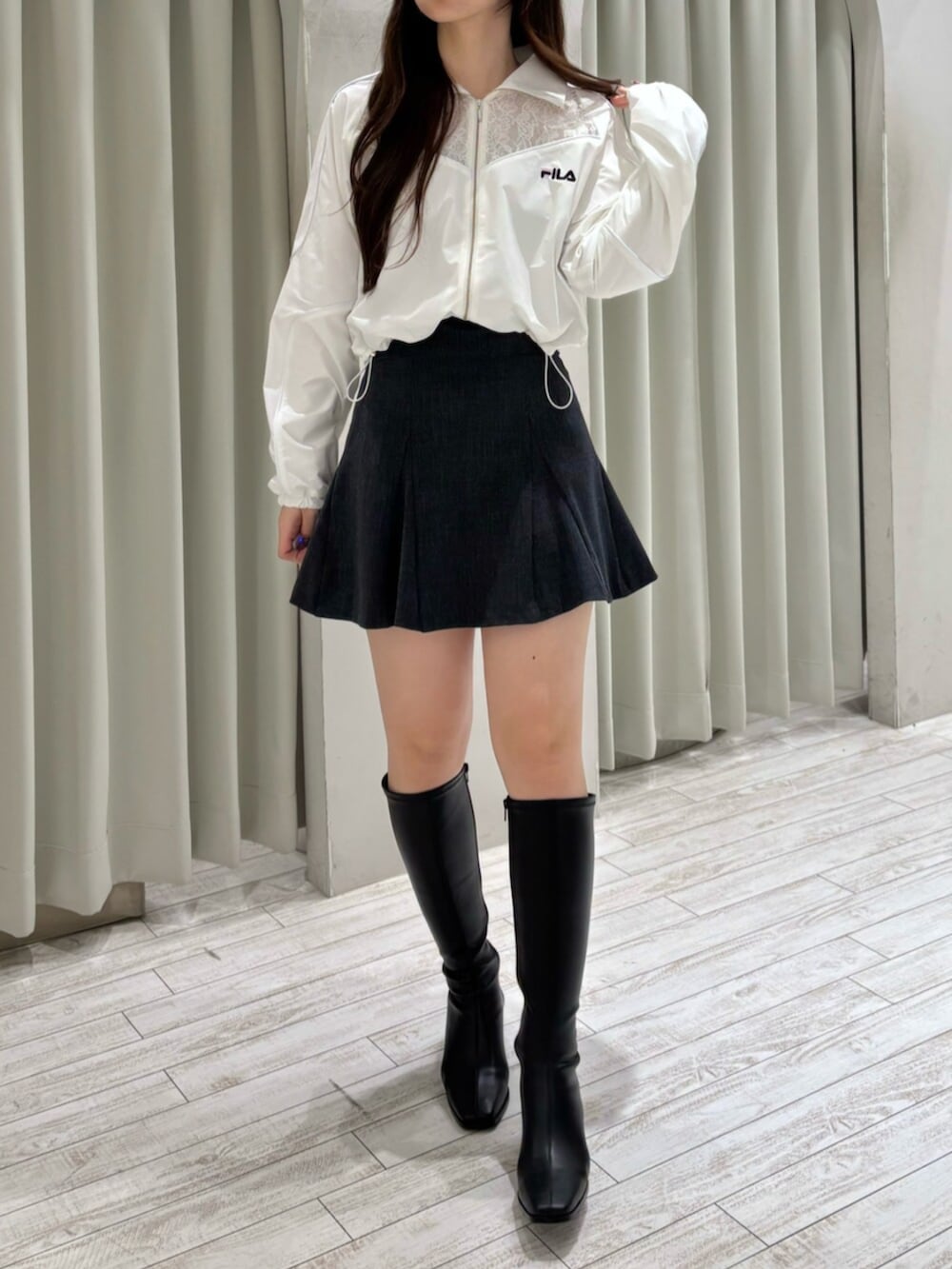 ブラック系のブーツ、ホワイト系のナイロンジャケット、グレー系のスカートを着用したレディースの冬コーディネートの2枚目の写真