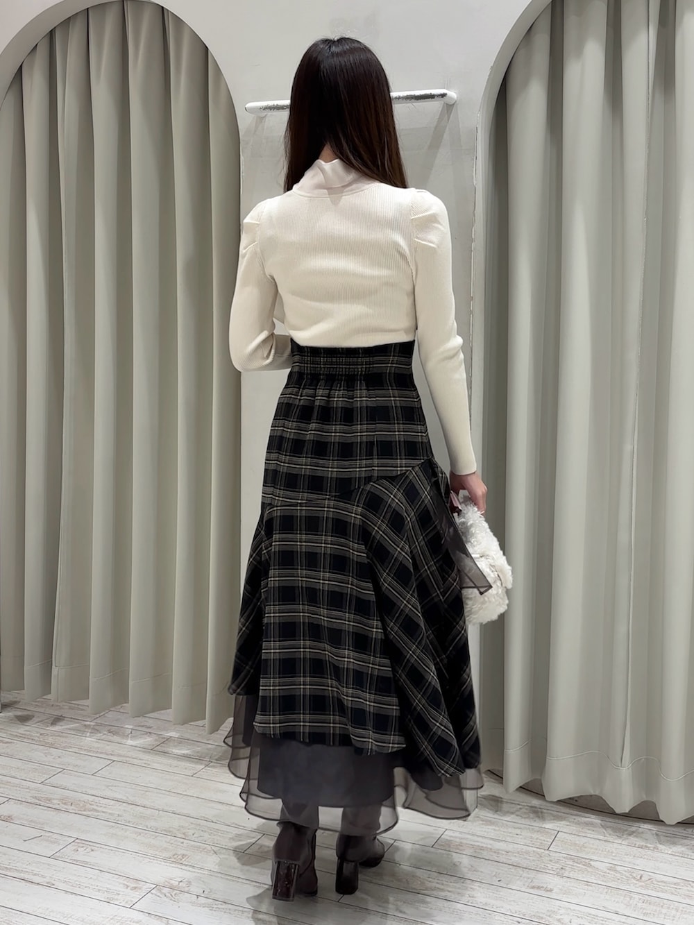 ホワイト系のニット/セーター、グレー系のスカート、ホワイト系のハンドバッグを着用したレディースの冬コーディネートの5枚目の写真