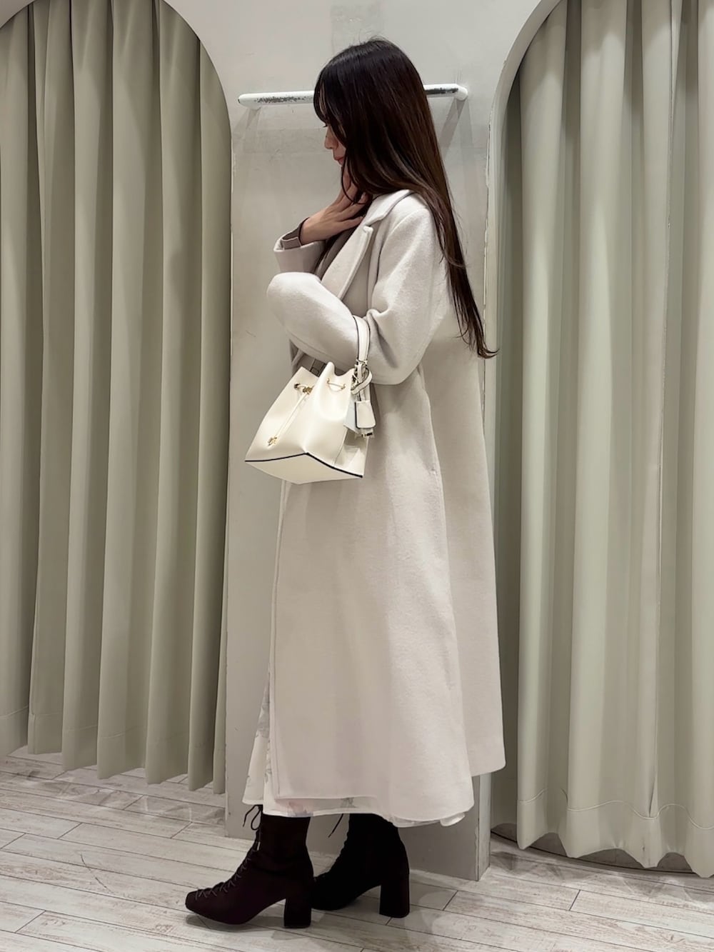 ベージュ系のワンピース、ホワイト系のショルダーバッグ、ホワイト系のチェスターコートを着用したレディースの秋コーディネートの4枚目の写真