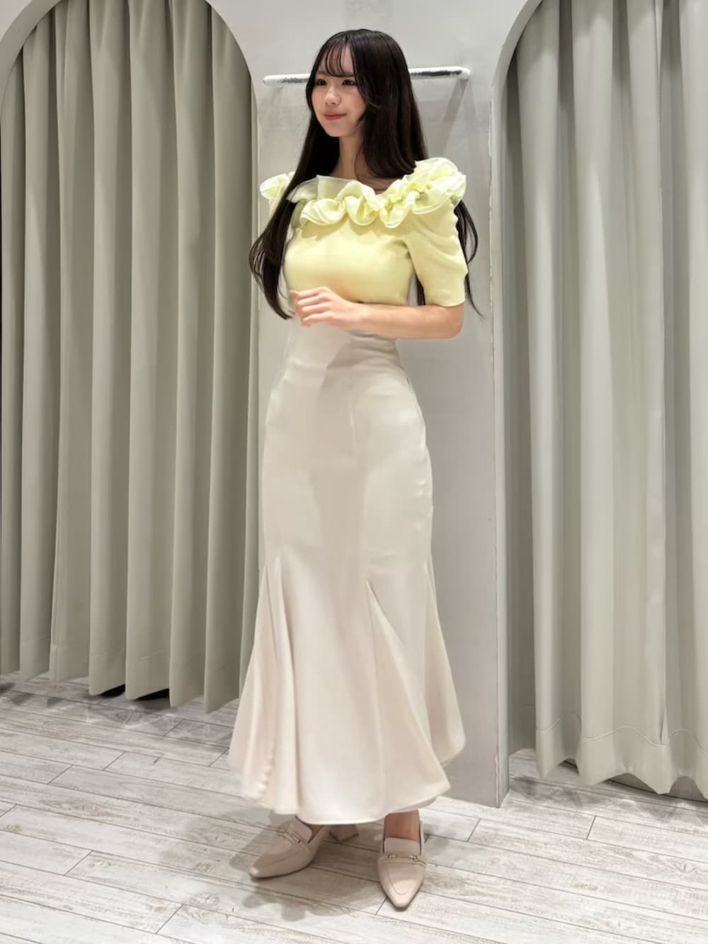 ホワイト系のスカート、ホワイト系のパンプス、イエロー系のニット/セーターを着用したレディースの春コーディネートの2枚目の写真