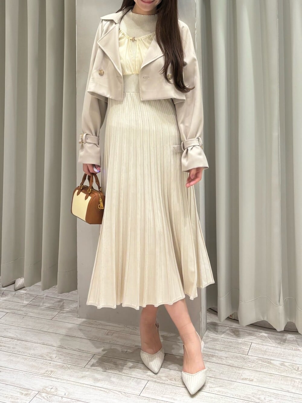 ブラウン系のハンドバッグ、ホワイト系のパンプス、ベージュ系のトレンチコートを着用したレディースの春コーディネートの3枚目の写真