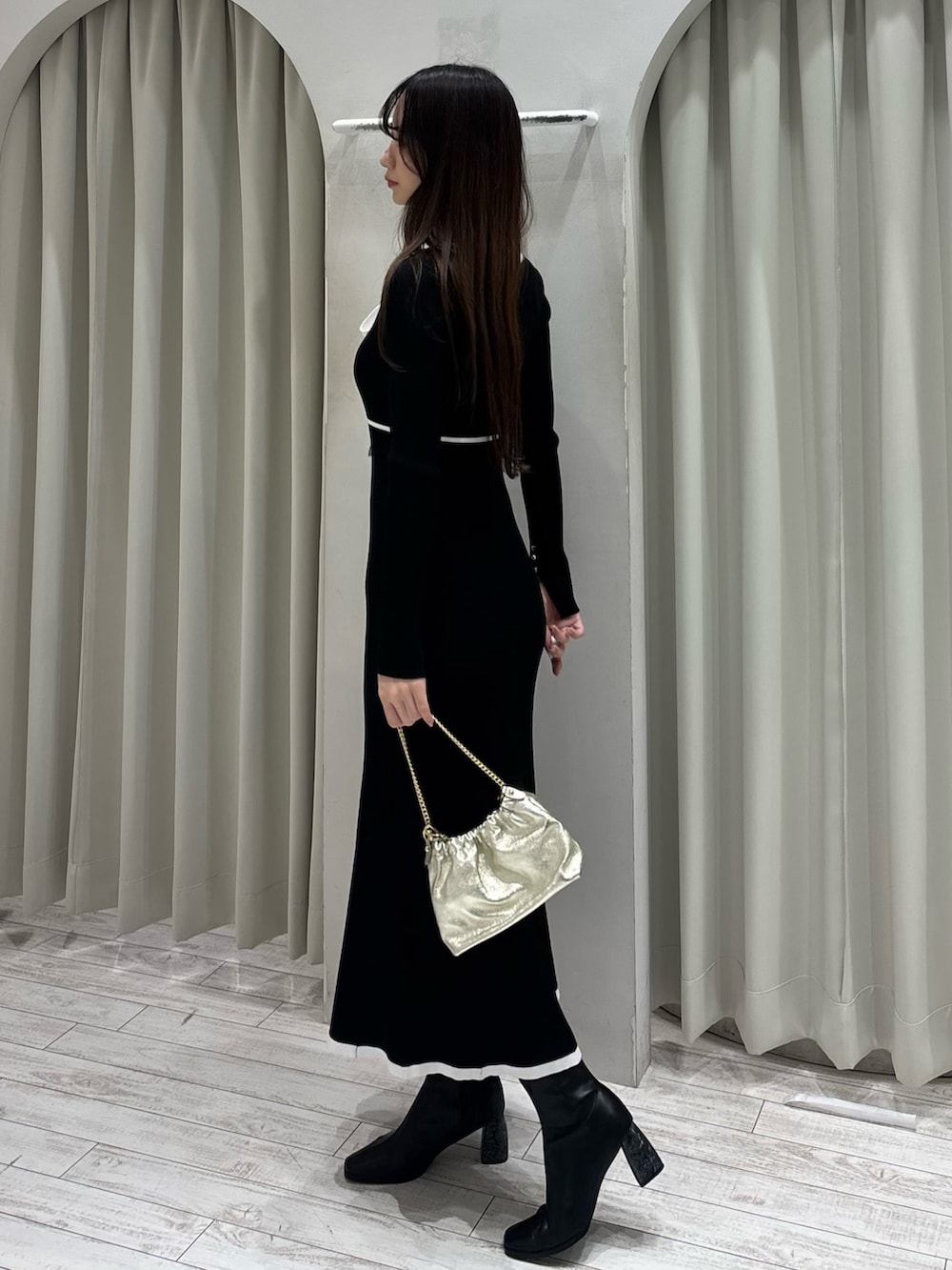 ブラック系のワンピース、ゴールド系のショルダーバッグ、ブラック系のブーツを着用したレディースの冬コーディネートの5枚目の写真