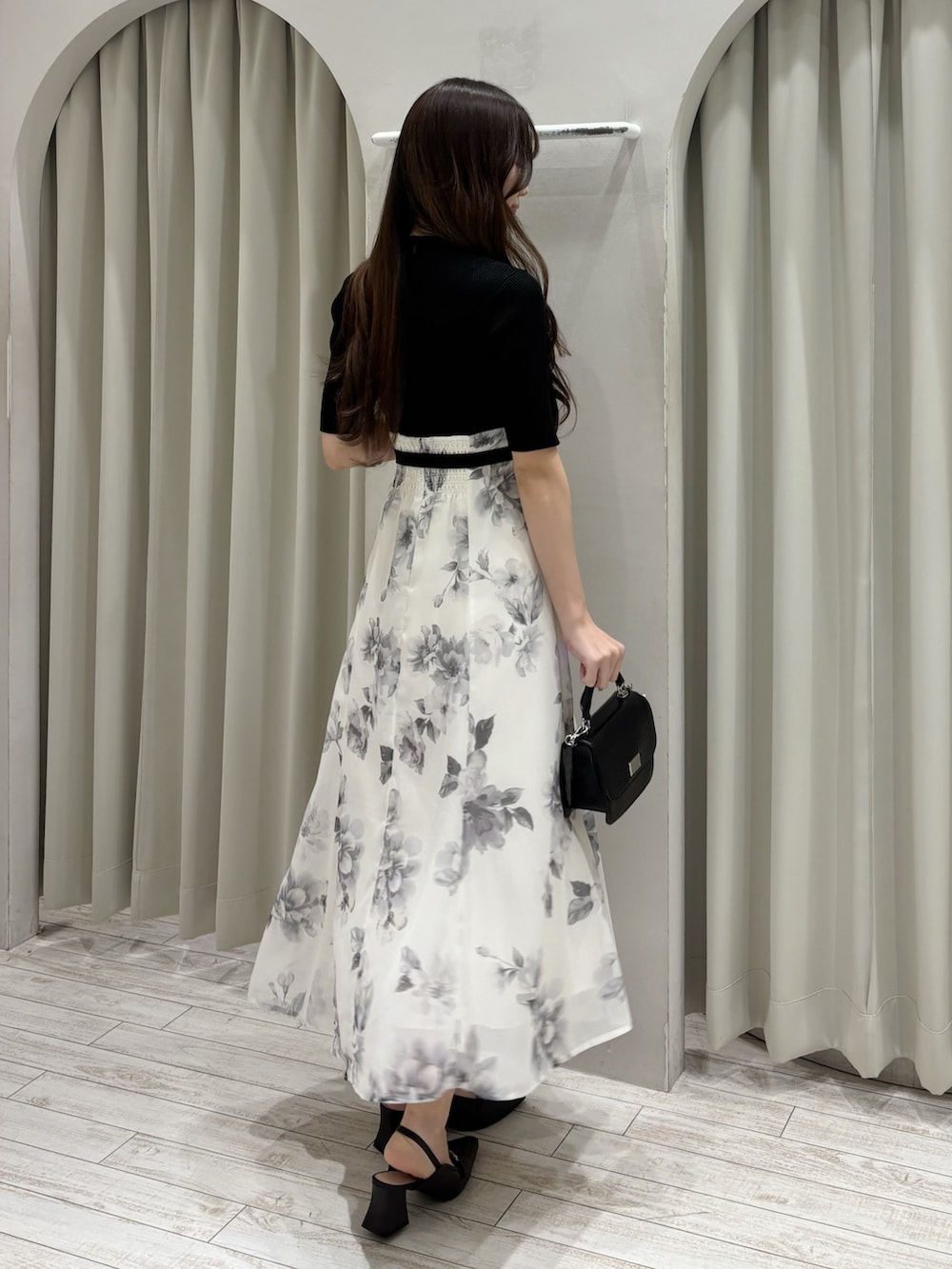 ブラック系のワンピース、ブラウン系のパンプス、ブラック系のハンドバッグを着用したレディースの春コーディネートの5枚目の写真