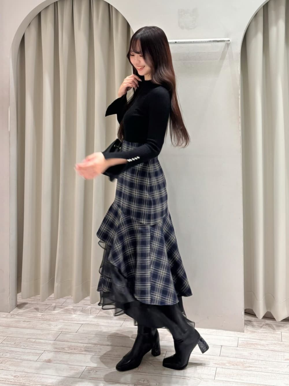 ブラック系のショルダーバッグ、ブラック系のニット/セーター、ブルー系のスカートを着用したレディースの冬コーディネートの2枚目の写真