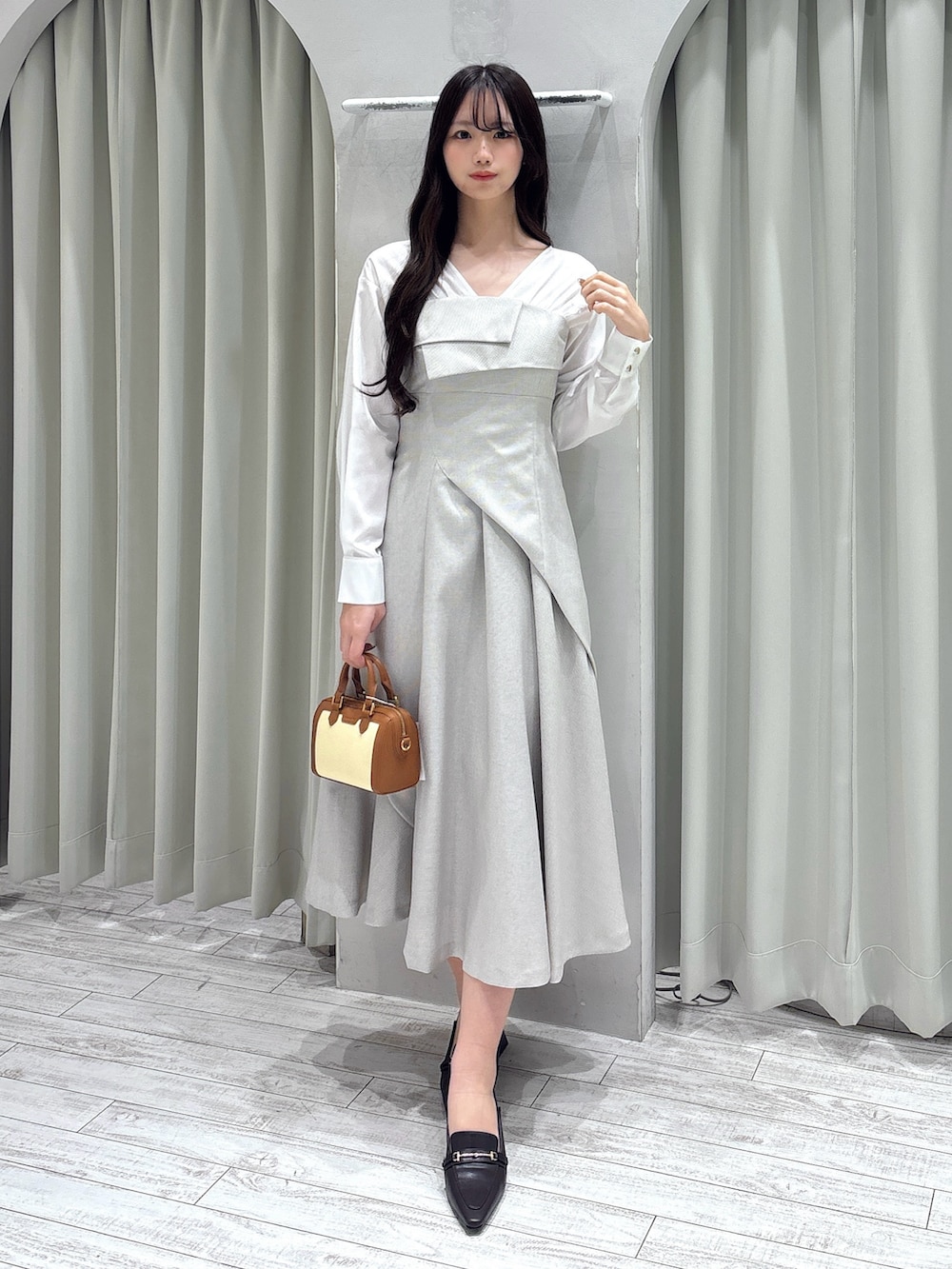 ベージュ系のワンピース、ブラウン系のハンドバッグ、ブラウン系のパンプスを着用したレディースの春コーディネートの2枚目の写真