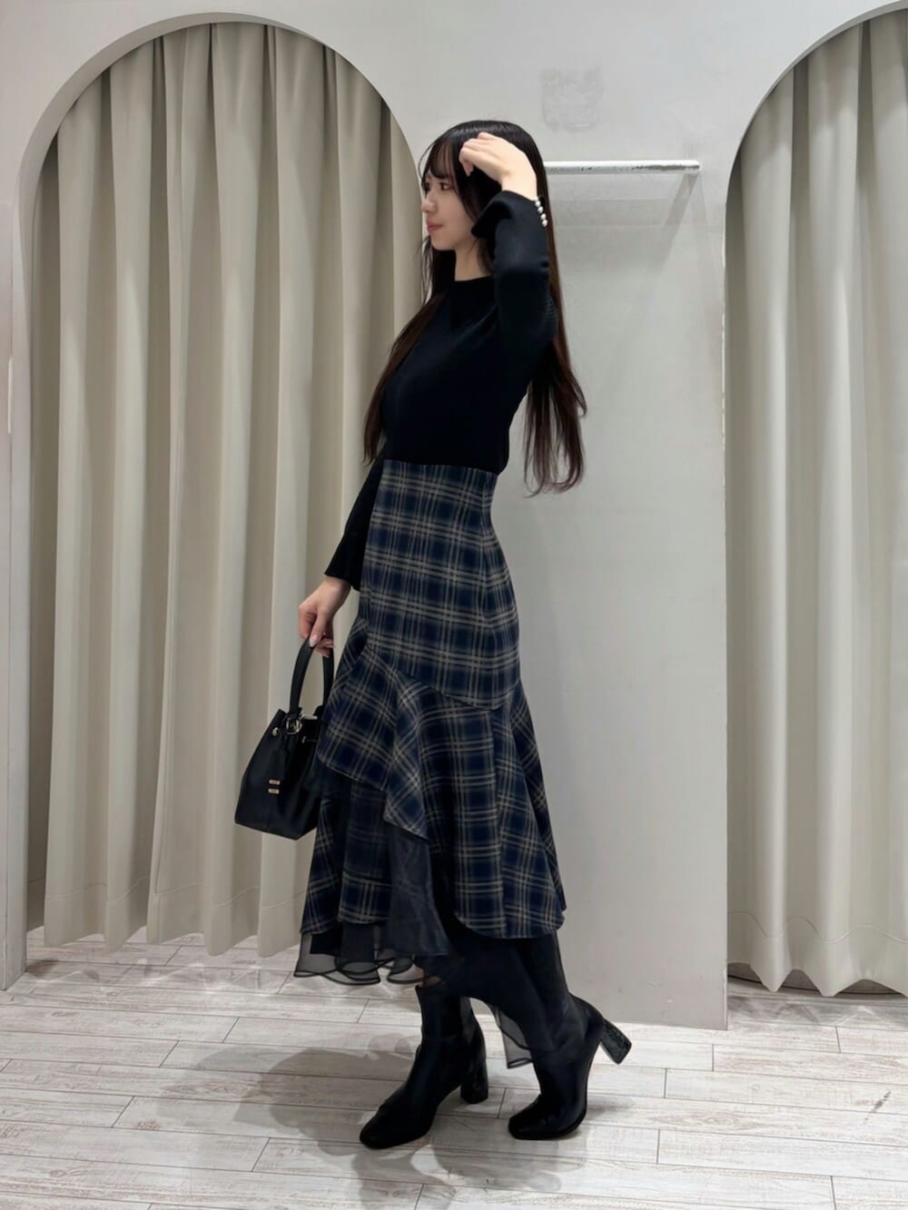 ブラック系のショルダーバッグ、ブラック系のニット/セーター、ブルー系のスカートを着用したレディースの冬コーディネートの5枚目の写真