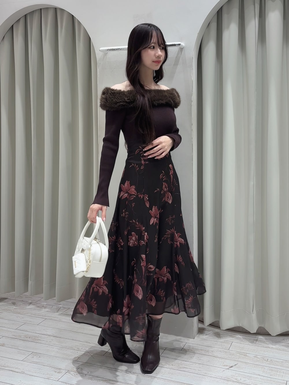 ブラウン系のワンピース、ホワイト系のハンドバッグ、ブラウン系のブーツを着用したレディースの冬コーディネートの5枚目の写真