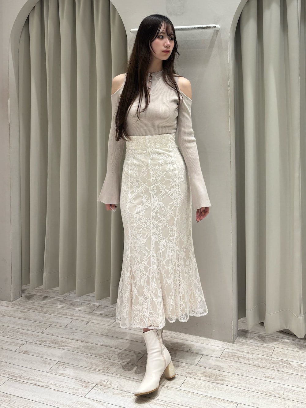 ベージュ系のニット/セーター、ホワイト系のスカート、ホワイト系のブーツを着用したレディースの春コーディネートの2枚目の写真