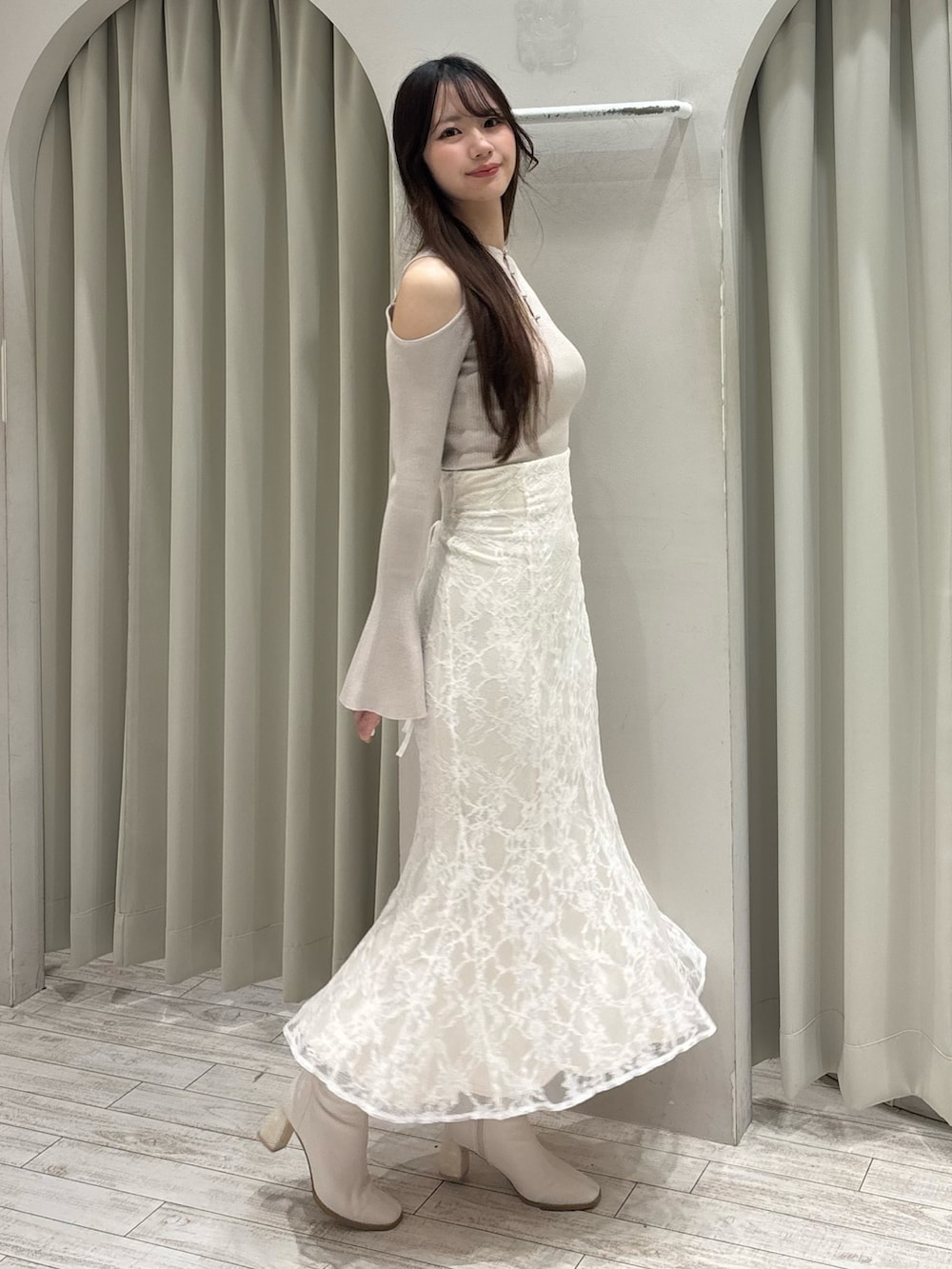 ベージュ系のニット/セーター、ホワイト系のスカート、ホワイト系のブーツを着用したレディースの春コーディネートの5枚目の写真