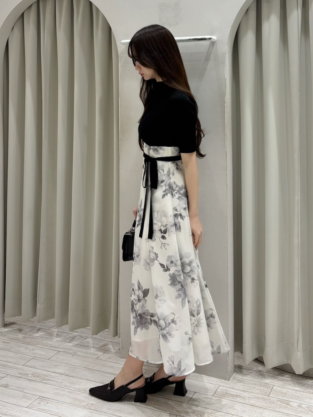 ブラック系のワンピース、ブラウン系のパンプス、ブラック系のハンドバッグを着用したレディースの春コーディネートの3枚目の写真