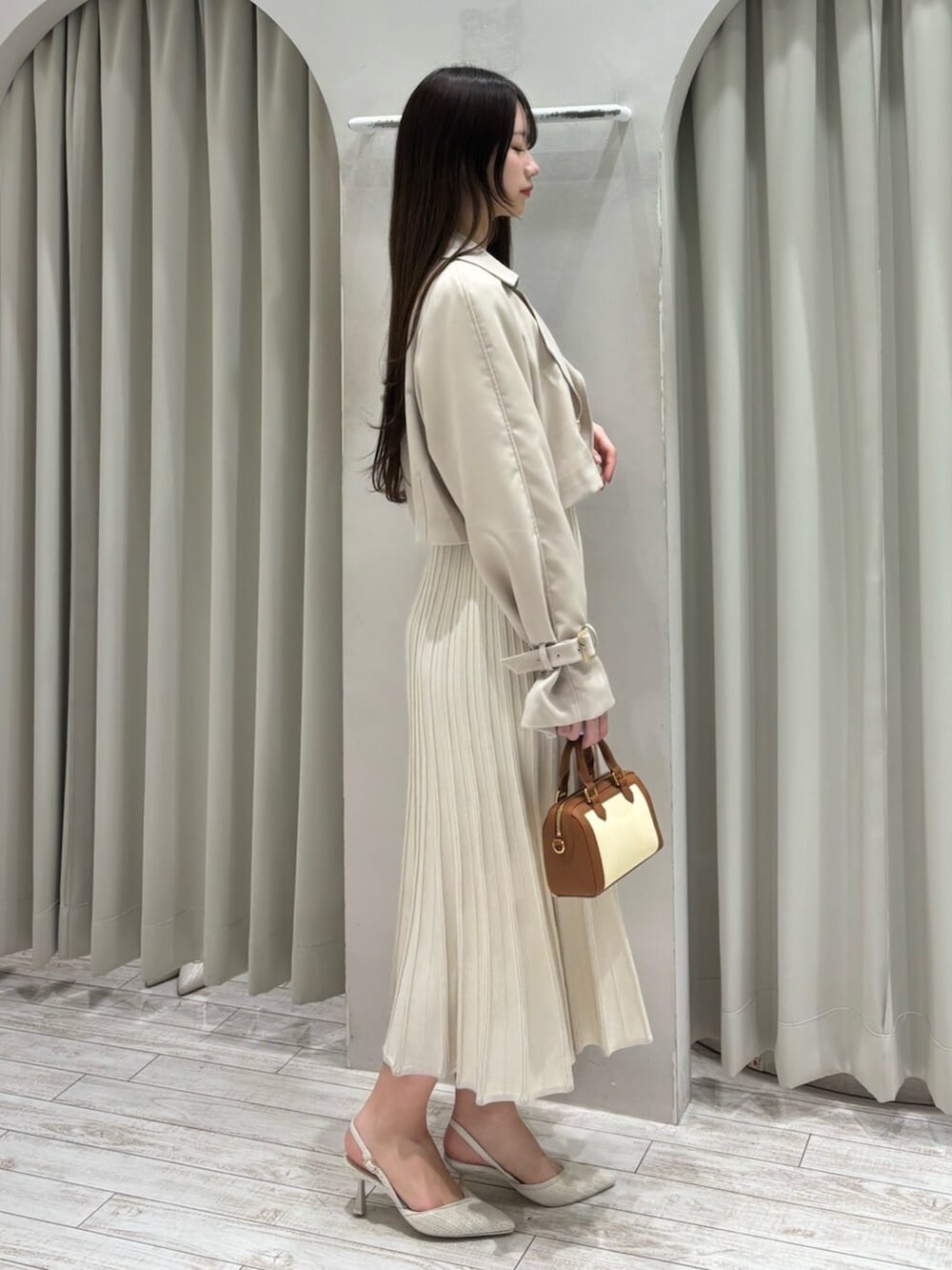 ブラウン系のハンドバッグ、ホワイト系のパンプス、ベージュ系のトレンチコートを着用したレディースの春コーディネートの5枚目の写真