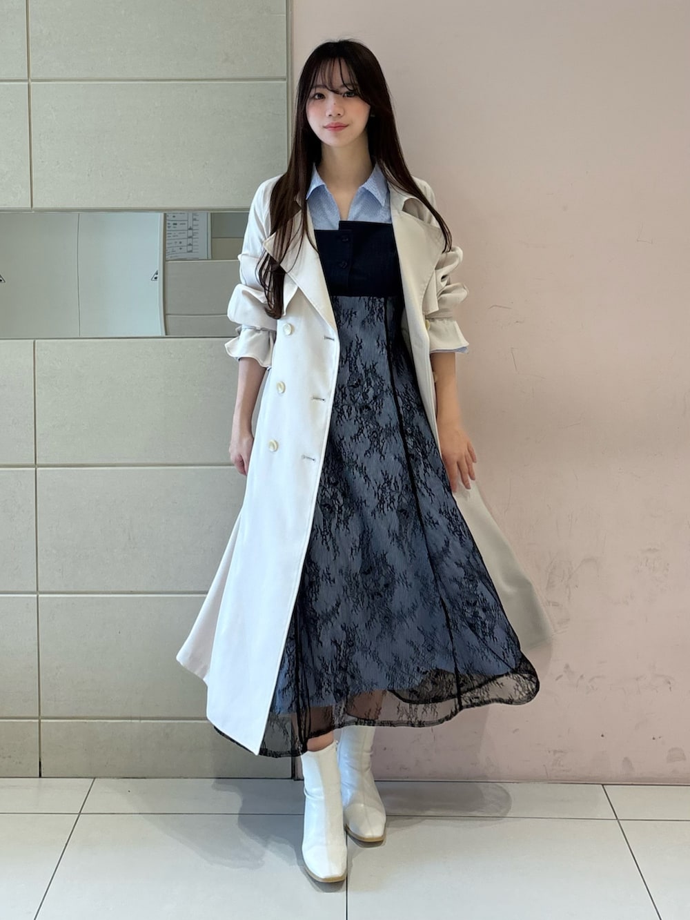 ブルー系のワンピース、ホワイト系のトレンチコート、ホワイト系のブーツを着用したレディースの冬コーディネートの2枚目の写真