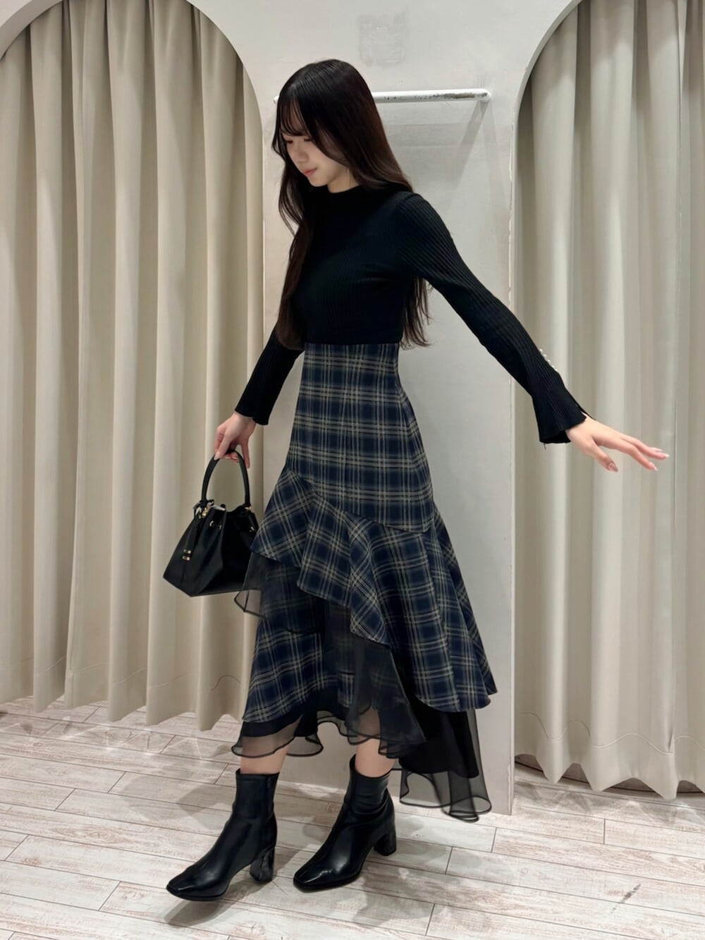 ブラック系のショルダーバッグ、ブラック系のニット/セーター、ブルー系のスカートを着用したレディースの冬コーディネートの3枚目の写真
