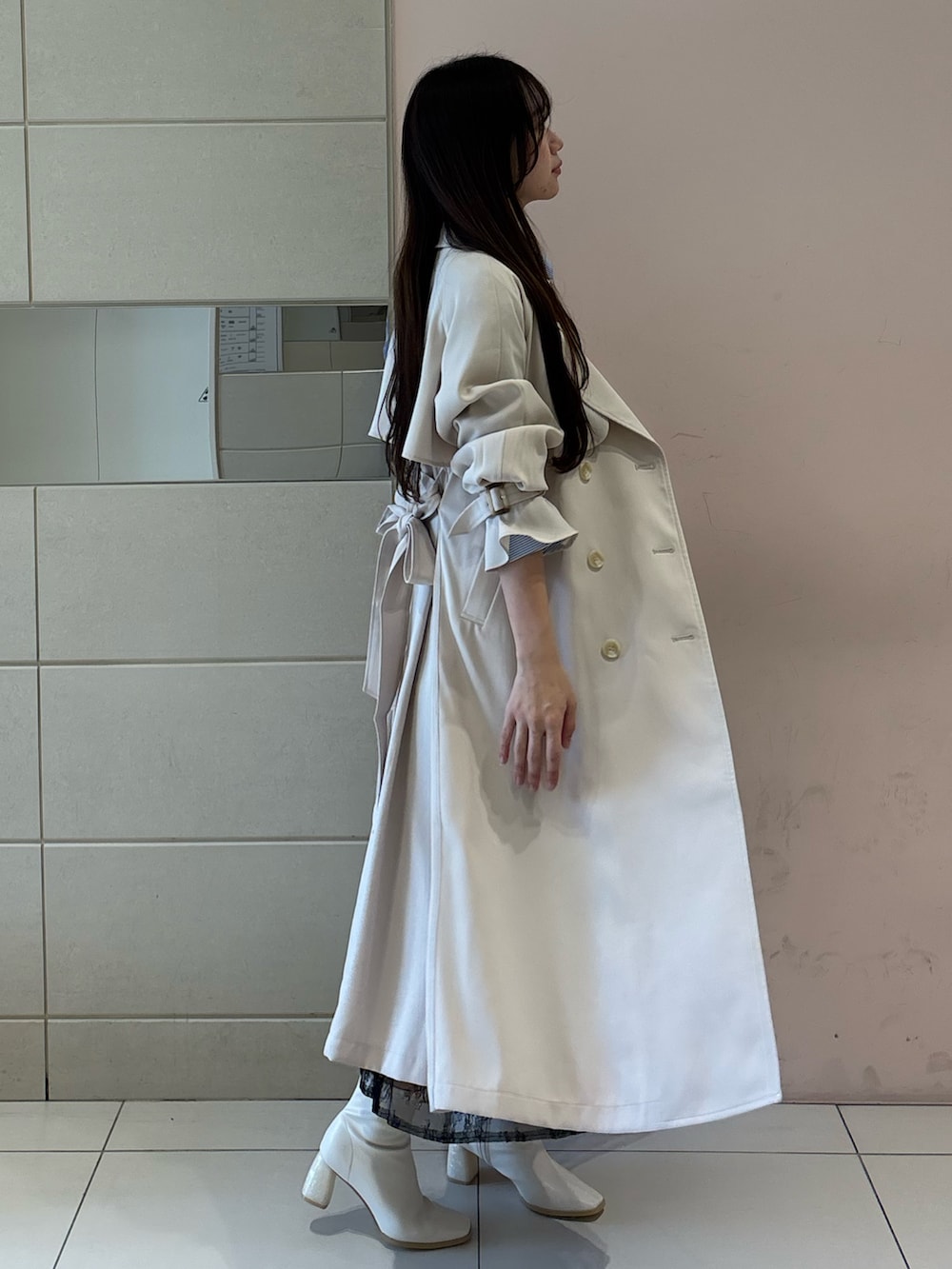 ブルー系のワンピース、ホワイト系のトレンチコート、ホワイト系のブーツを着用したレディースの冬コーディネートの4枚目の写真