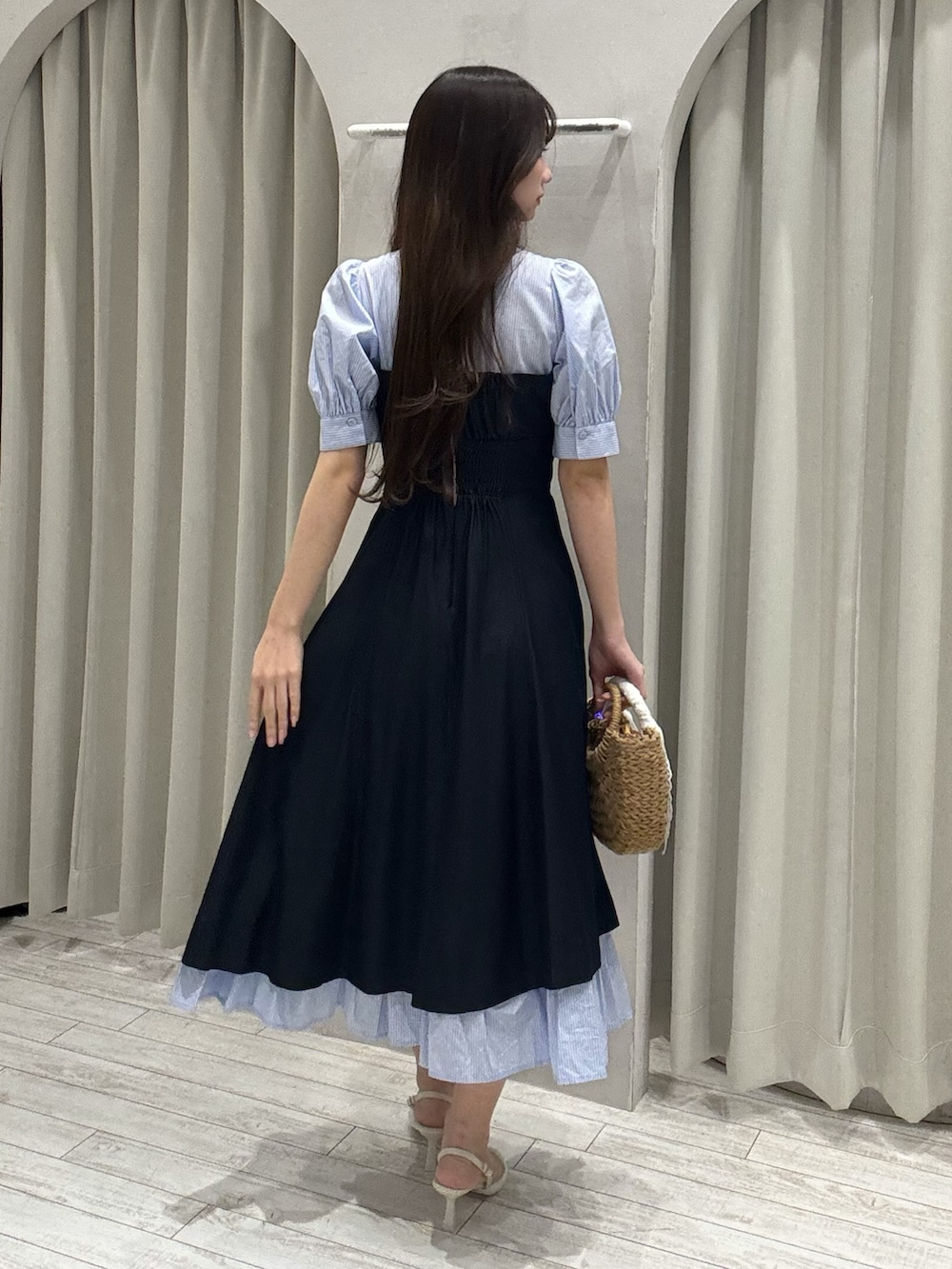 ブルー系のワンピース、ベージュ系のハンドバッグ、ホワイト系のパンプスを着用したレディースの春コーディネートの4枚目の写真