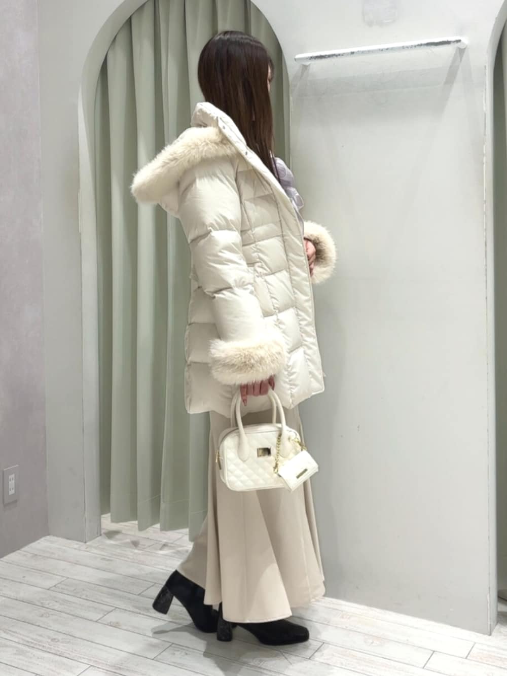 ホワイト系のハンドバッグ、ブラック系のブーツ、ホワイト系のダウンジャケット/コートを着用したレディースの秋コーディネートの6枚目の写真