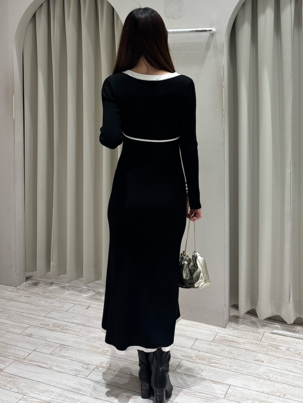 ブラック系のワンピース、ゴールド系のショルダーバッグ、ブラック系のブーツを着用したレディースの冬コーディネートの6枚目の写真