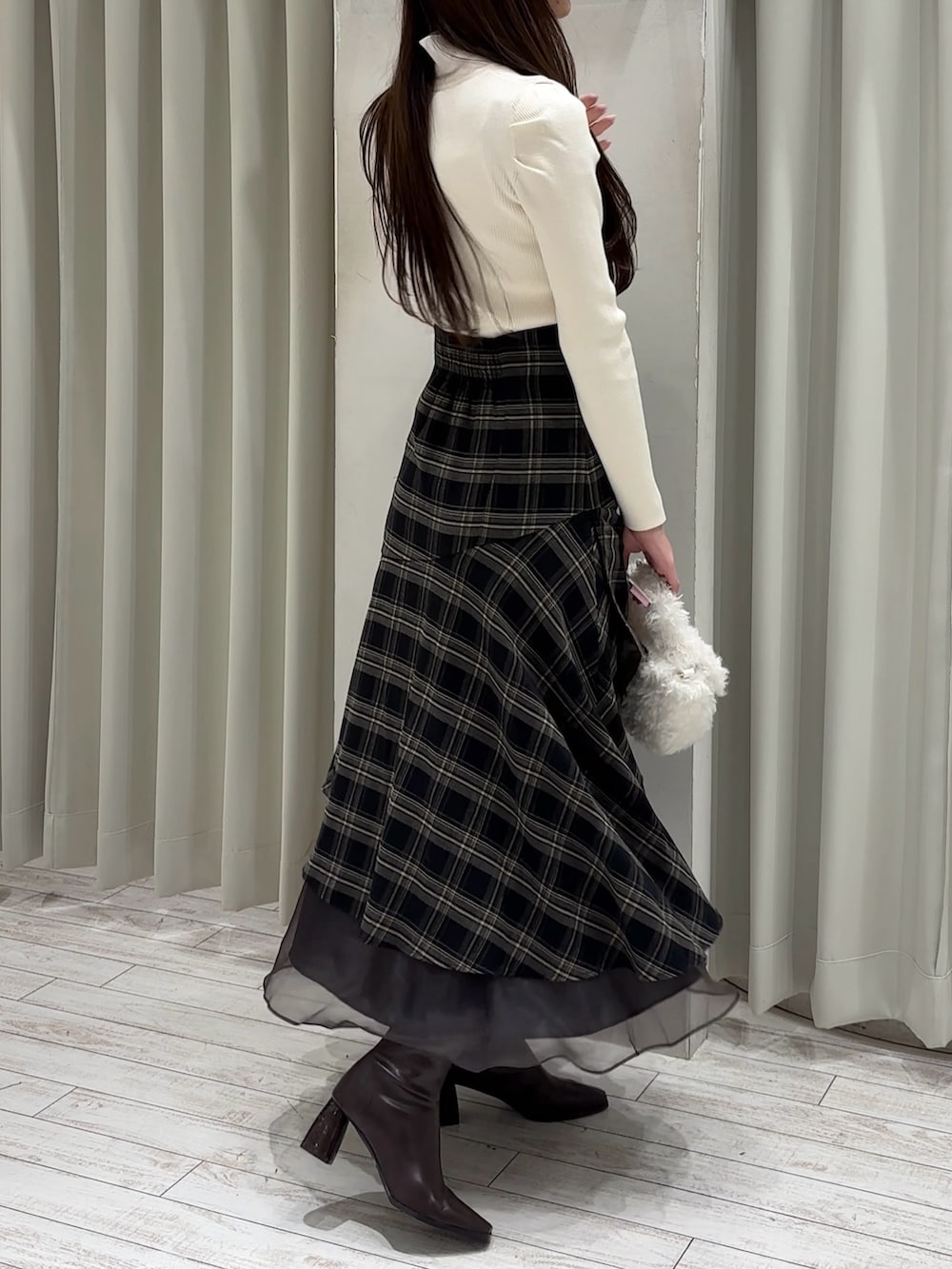 ホワイト系のニット/セーター、グレー系のスカート、ホワイト系のハンドバッグを着用したレディースの冬コーディネートの6枚目の写真