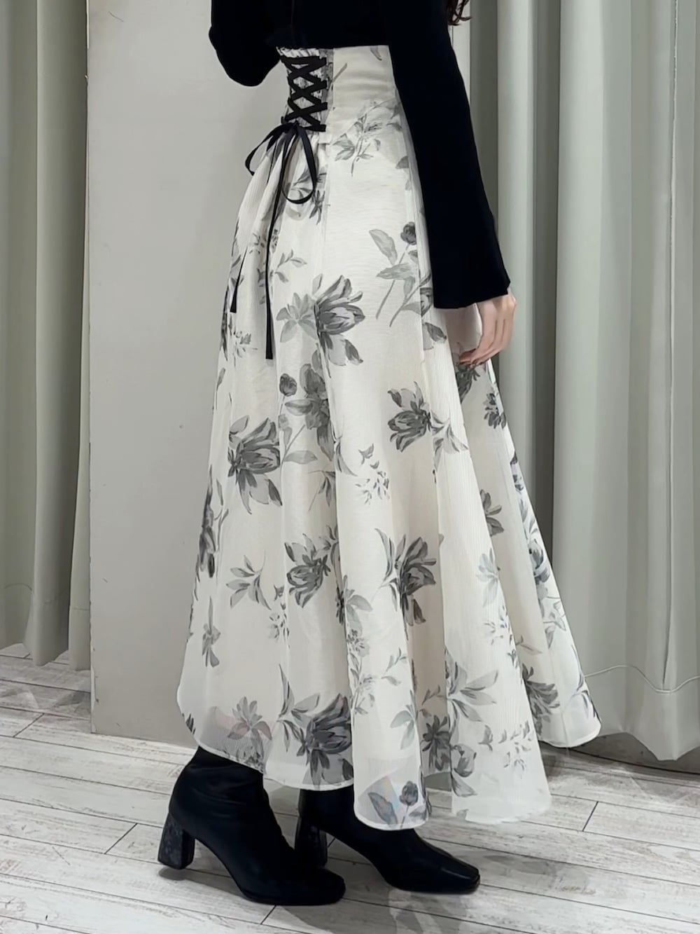 ブラック系のニット/セーター、ホワイト系のスカート、ブラック系のブーツを着用したレディースの春コーディネートの5枚目の写真