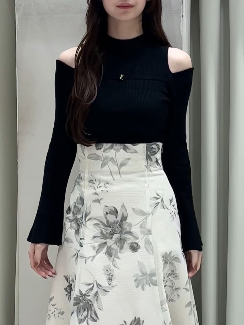 ブラック系のニット/セーター、ホワイト系のスカート、ブラック系のブーツを着用したレディースの春コーディネートの3枚目の写真