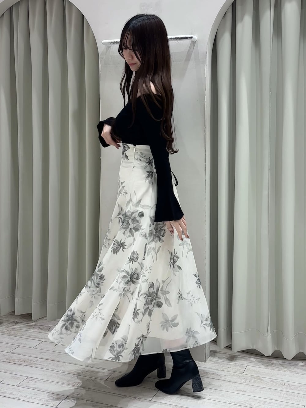 ブラック系のニット/セーター、ホワイト系のスカート、ブラック系のブーツを着用したレディースの春コーディネートの4枚目の写真