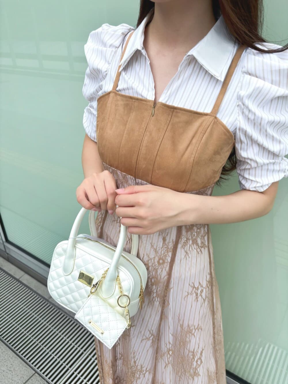 ベージュ系のワンピース、ホワイト系のハンドバッグ、ホワイト系のパンプスを着用したレディースの秋コーディネートの5枚目の写真