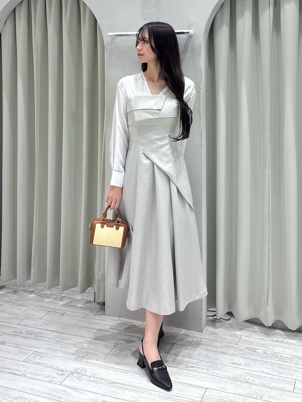 ベージュ系のワンピース、ブラウン系のハンドバッグ、ブラウン系のパンプスを着用したレディースの春コーディネートの3枚目の写真