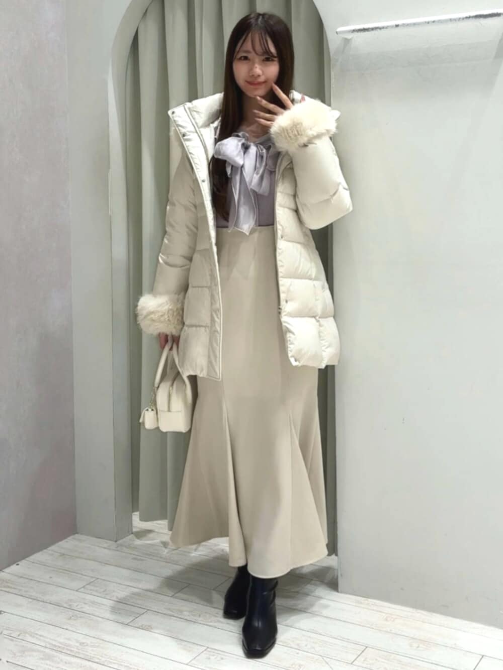 ホワイト系のハンドバッグ、ブラック系のブーツ、ホワイト系のダウンジャケット/コートを着用したレディースの秋コーディネートの2枚目の写真