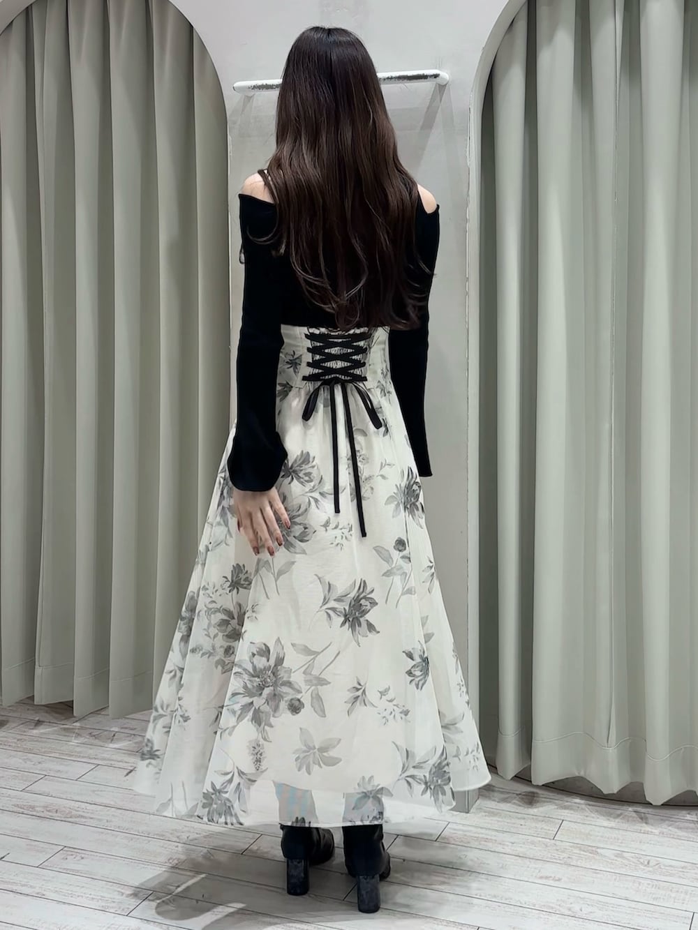 ブラック系のニット/セーター、ホワイト系のスカート、ブラック系のブーツを着用したレディースの春コーディネートの6枚目の写真