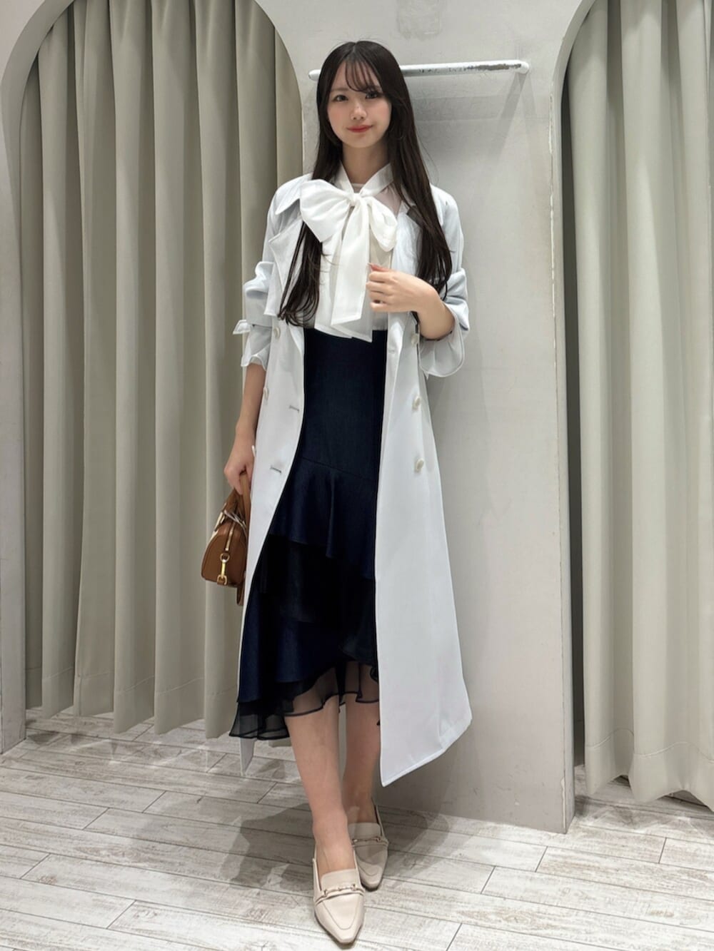 ホワイト系のパンプス、ホワイト系のシャツ/ブラウス、ブラウン系のハンドバッグを着用したレディースの春コーディネートの2枚目の写真