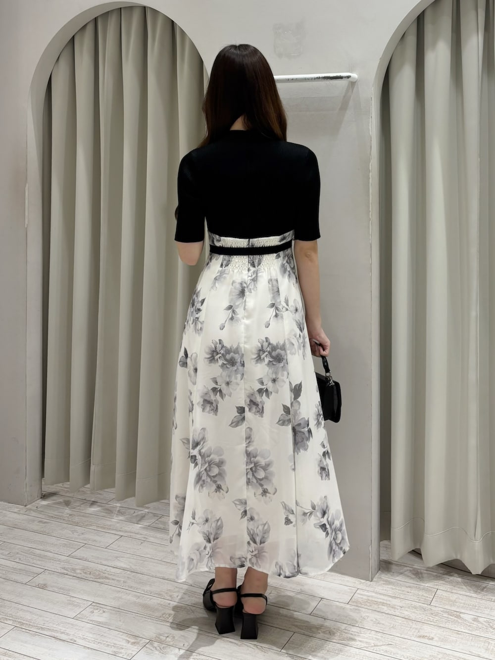 ブラック系のワンピース、ブラウン系のパンプス、ブラック系のハンドバッグを着用したレディースの春コーディネートの4枚目の写真