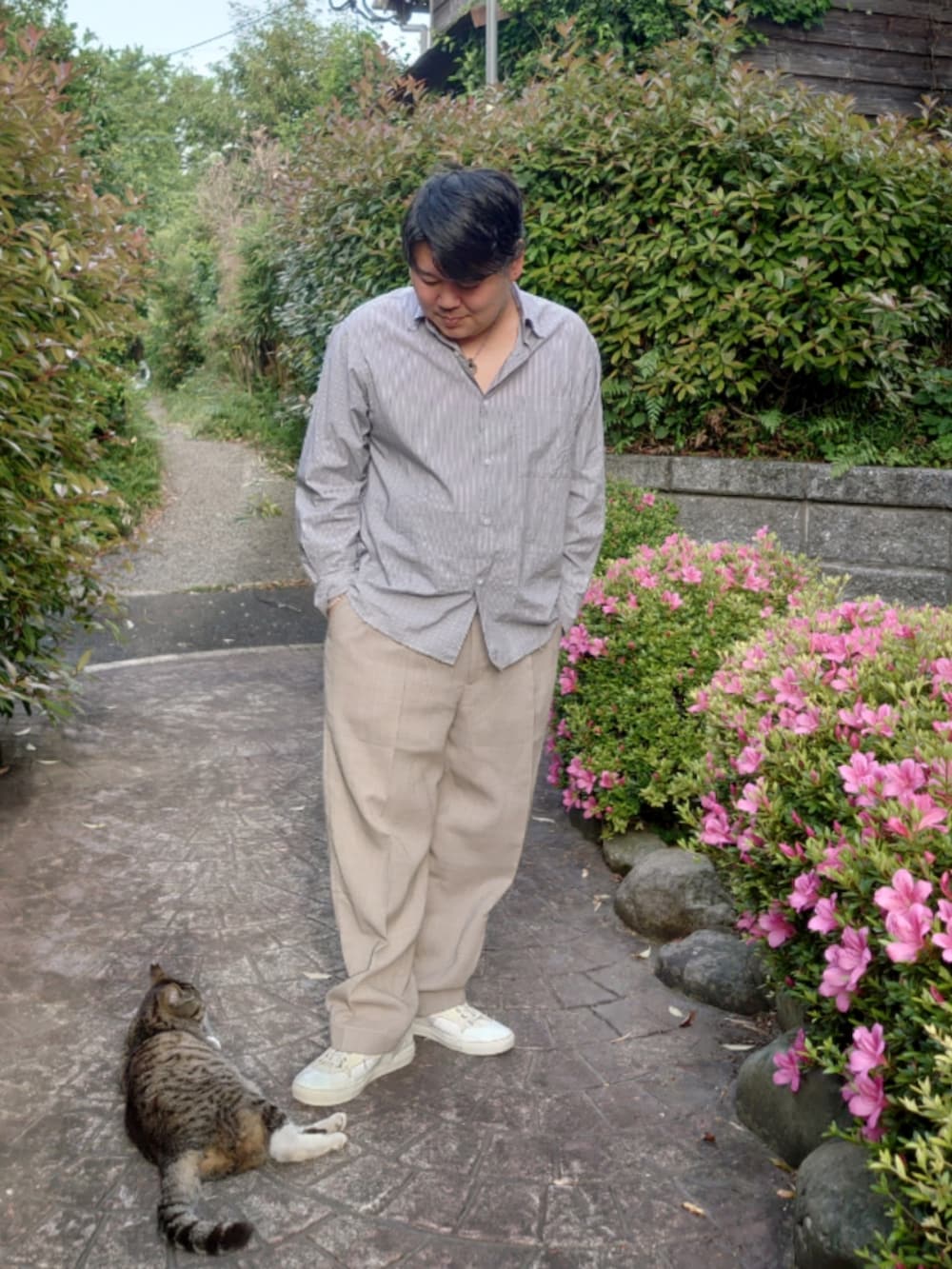 ブルー系のシャツ/ブラウス、ベージュ系のスラックス、ホワイト系のスニーカーを着用したメンズの春コーディネートの2枚目の写真