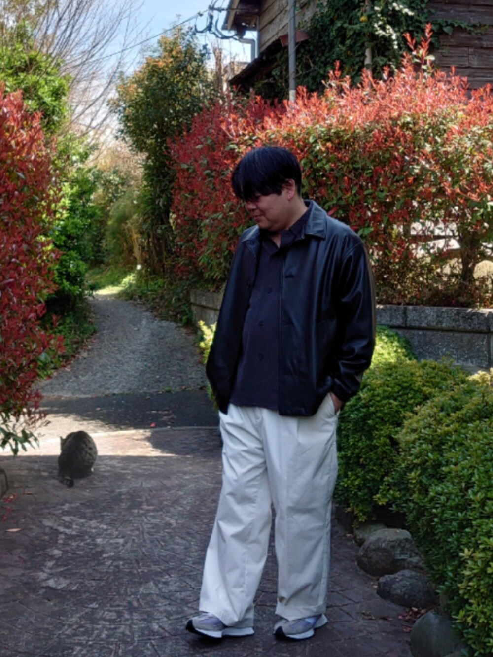 ブラック系のその他アウター、ホワイト系のスラックス、グレー系のシャツ/ブラウスを着用したメンズの春コーディネートの2枚目の写真