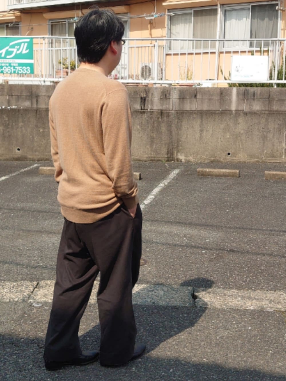 ブラウン系のニット/セーター、ブラック系のドレスシューズ、ブラック系のスラックスを着用したメンズの春コーディネートの3枚目の写真