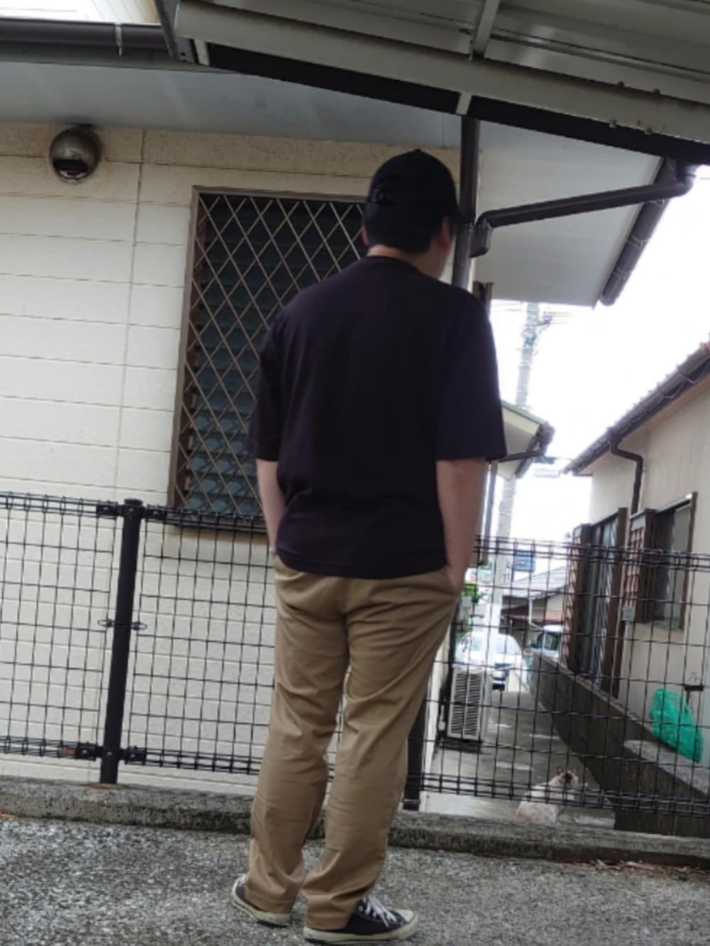 ブラック系のTシャツ/カットソー、ベージュ系のチノパンツ、ブラック系のスニーカーを着用したメンズの夏コーディネートの2枚目の写真