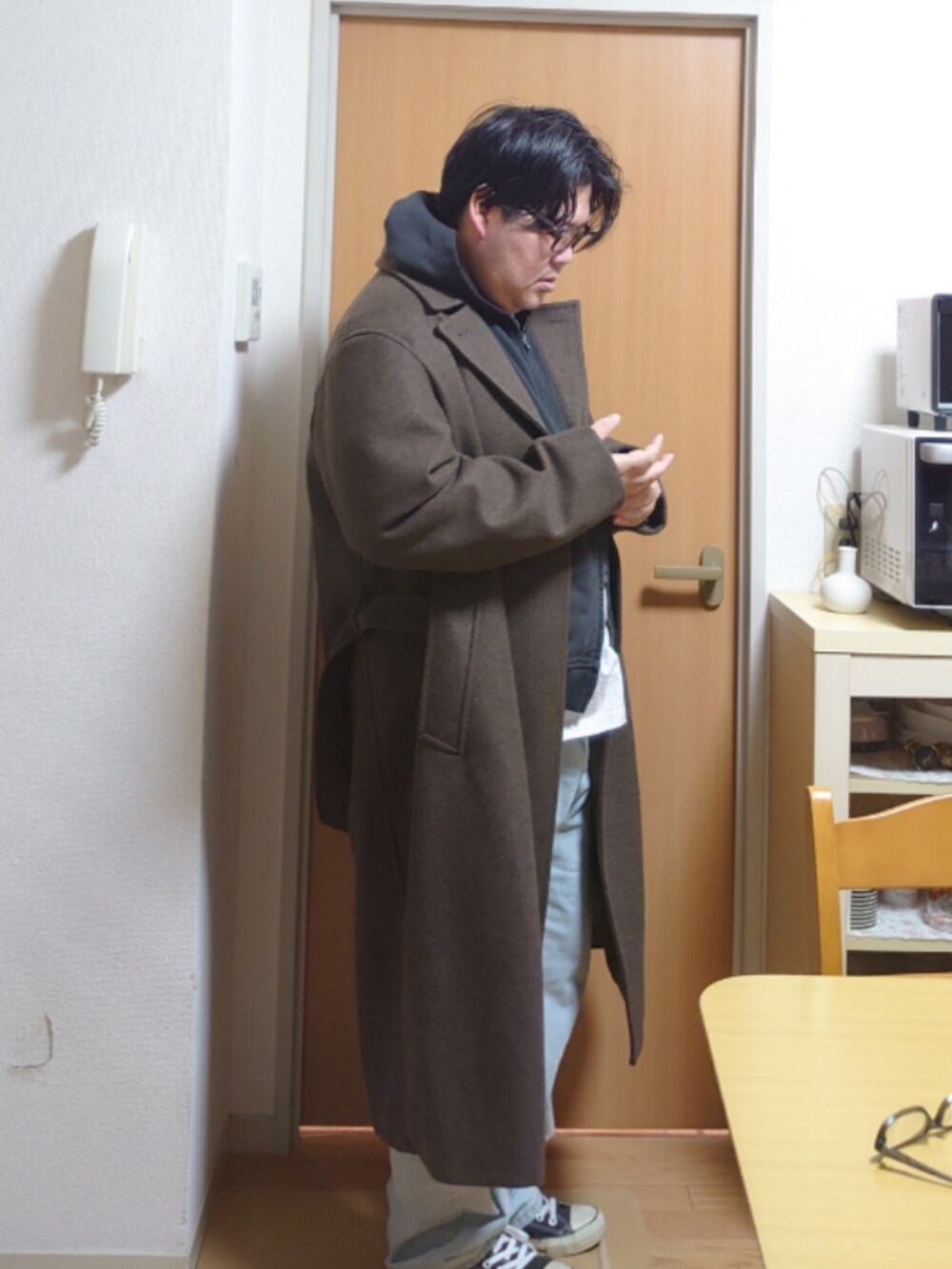 ブラック系のパーカー、ブラウン系のチェスターコート、グレー系のTシャツ/カットソーを着用したメンズの冬コーディネートの2枚目の写真