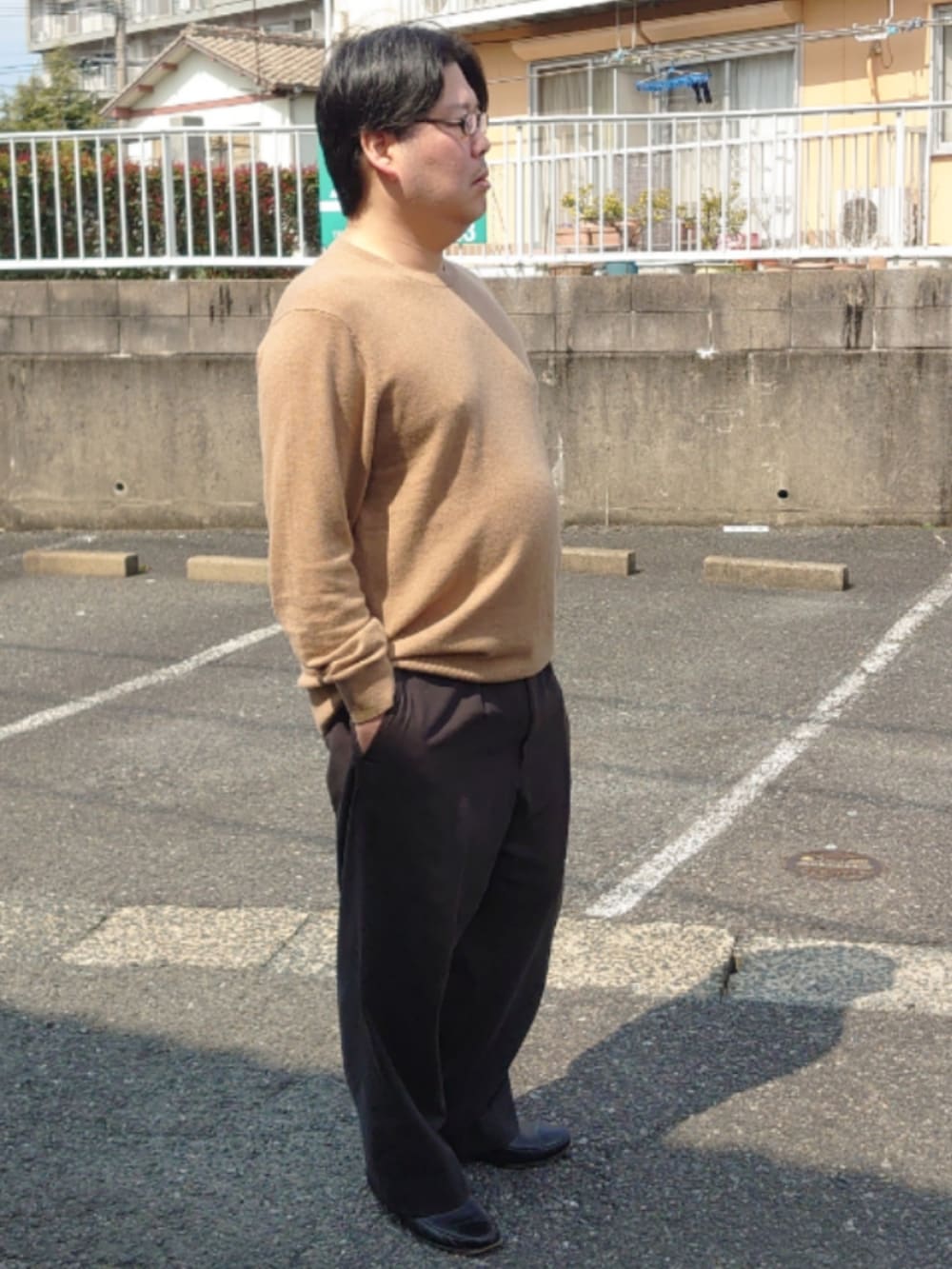 ブラウン系のニット/セーター、ブラック系のドレスシューズ、ブラック系のスラックスを着用したメンズの春コーディネートの2枚目の写真