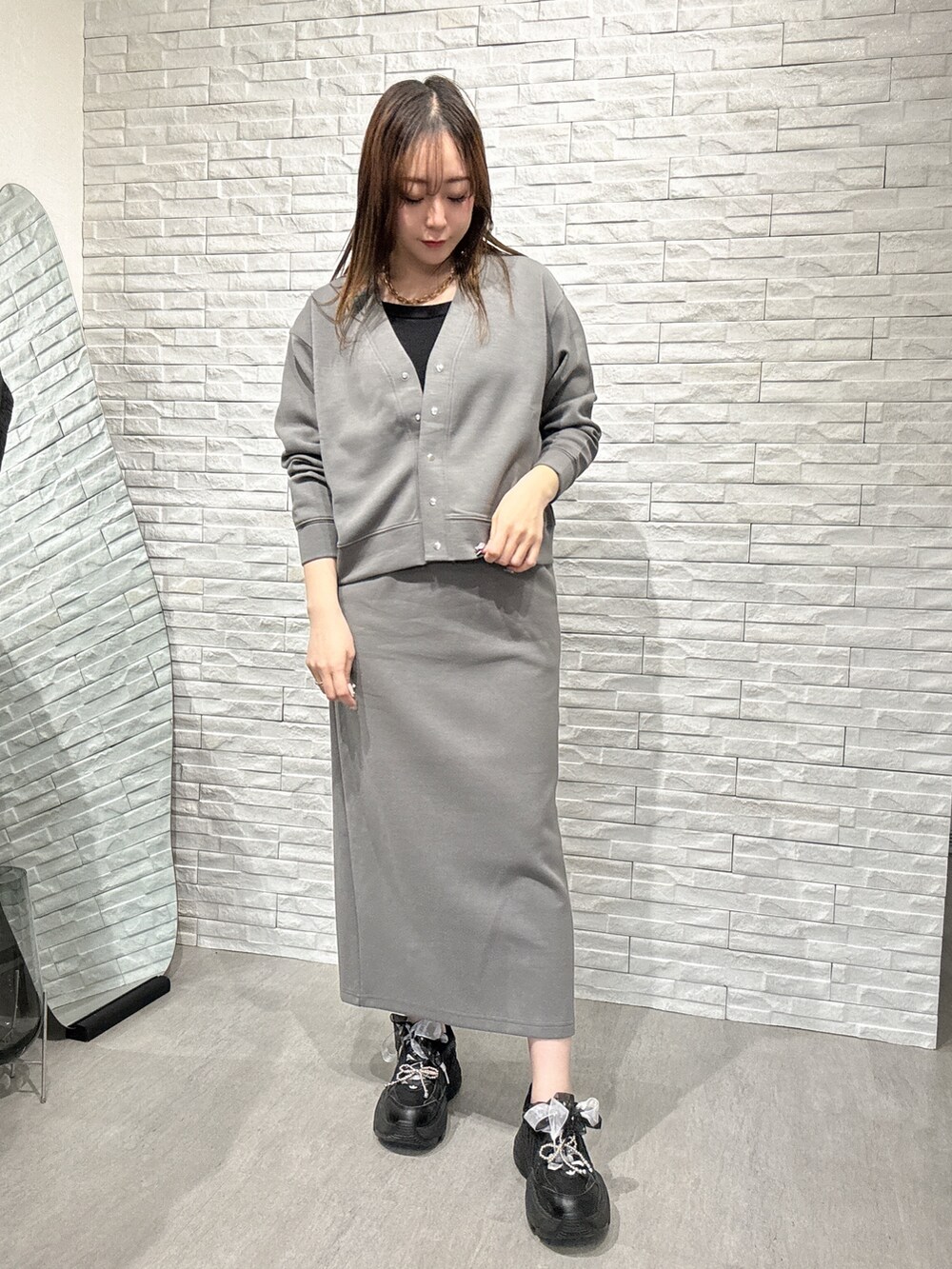 グレー系のスカート、グレー系のカーディガン/ボレロ、ブラック系のタンクトップを着用したレディースの春コーディネートの3枚目の写真