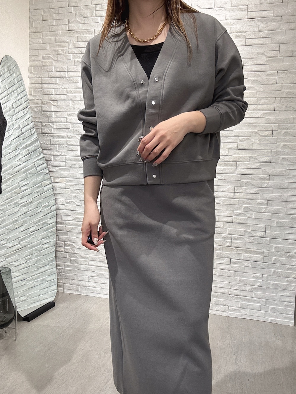 グレー系のスカート、グレー系のカーディガン/ボレロ、ブラック系のタンクトップを着用したレディースの春コーディネートの4枚目の写真