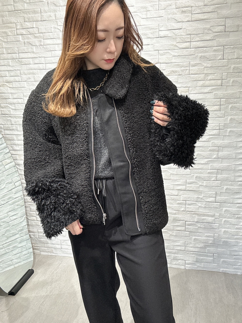 ブラック系のムートンコート、グレー系のニット/セーター、ブラック系のその他パンツを着用したレディースの冬コーディネートの4枚目の写真