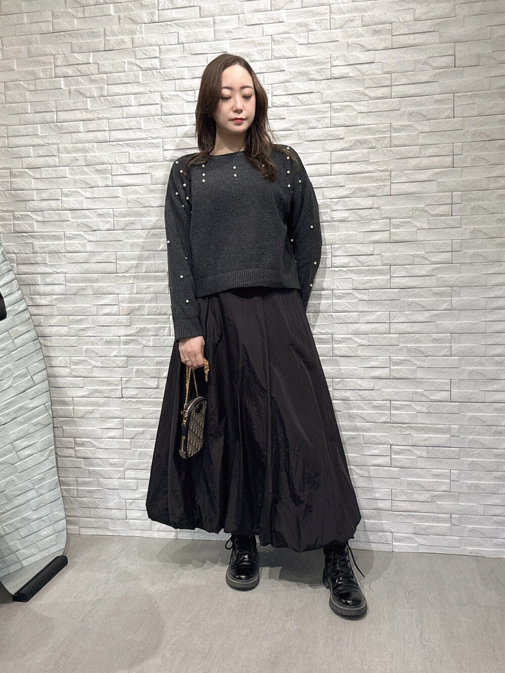 グレー系のニット/セーター、ブラック系のスカートを着用したレディースの冬コーディネートの2枚目の写真