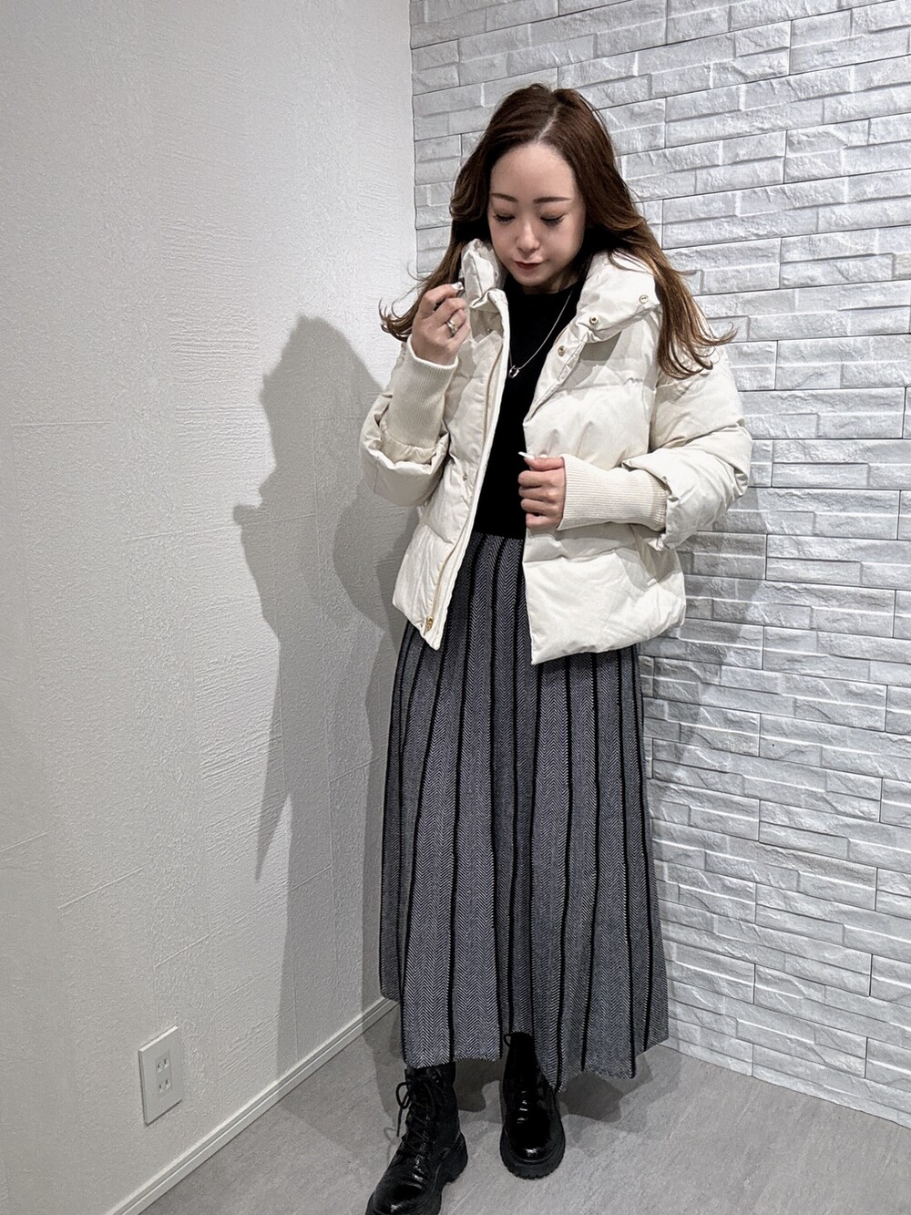 ホワイト系のダウンジャケット/コート、ブラック系のニット/セーターを着用したレディースの秋コーディネートの2枚目の写真