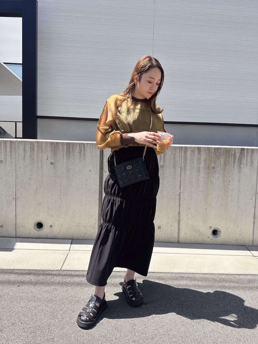 ブラウン系のシャツ/ブラウス、ブラック系のキャミソール、ブラック系のスカートを着用したレディースの春コーディネートの2枚目の写真